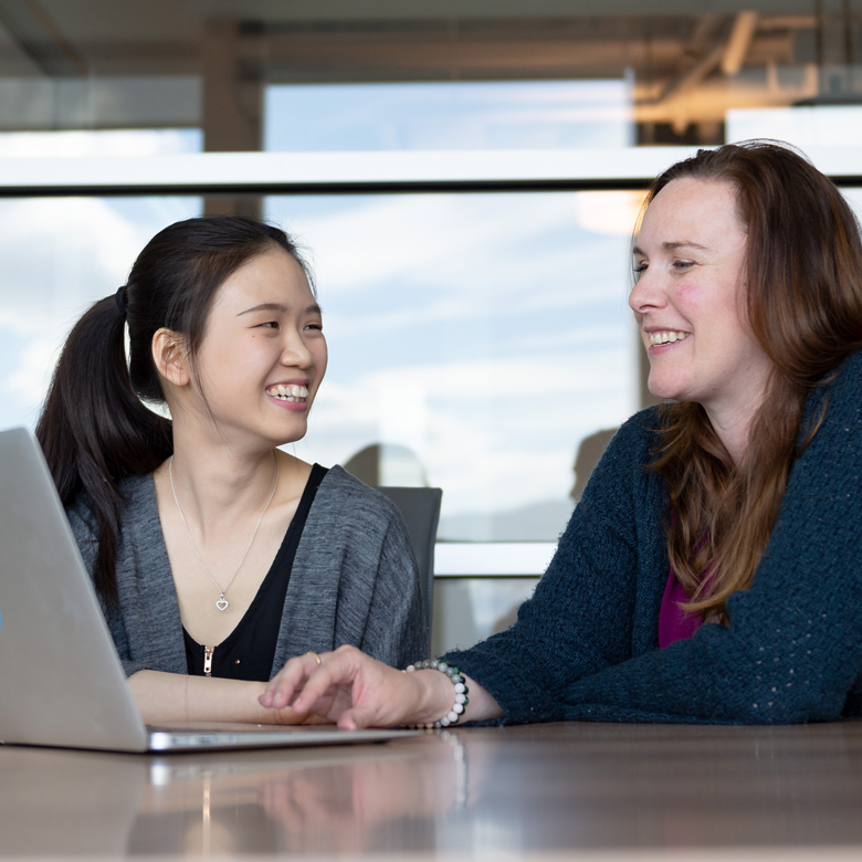 A student and an employer speaking at a desk with an open laptop.