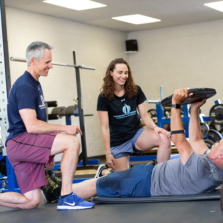 An employer and student in a gym working with a client.