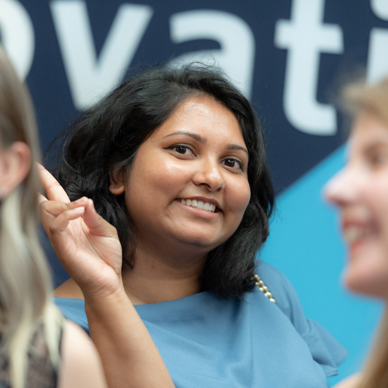 A student smiling at the camera through a crowd.