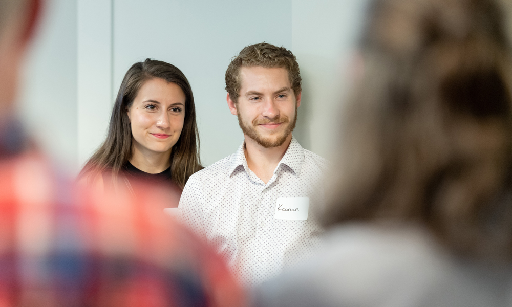 Two individuals listening to a speaker.